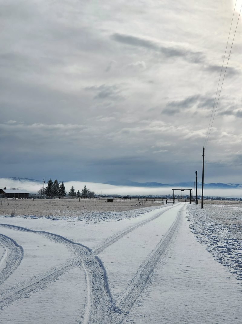 Tire tracks on a snow-covered gravel road running to the horizon